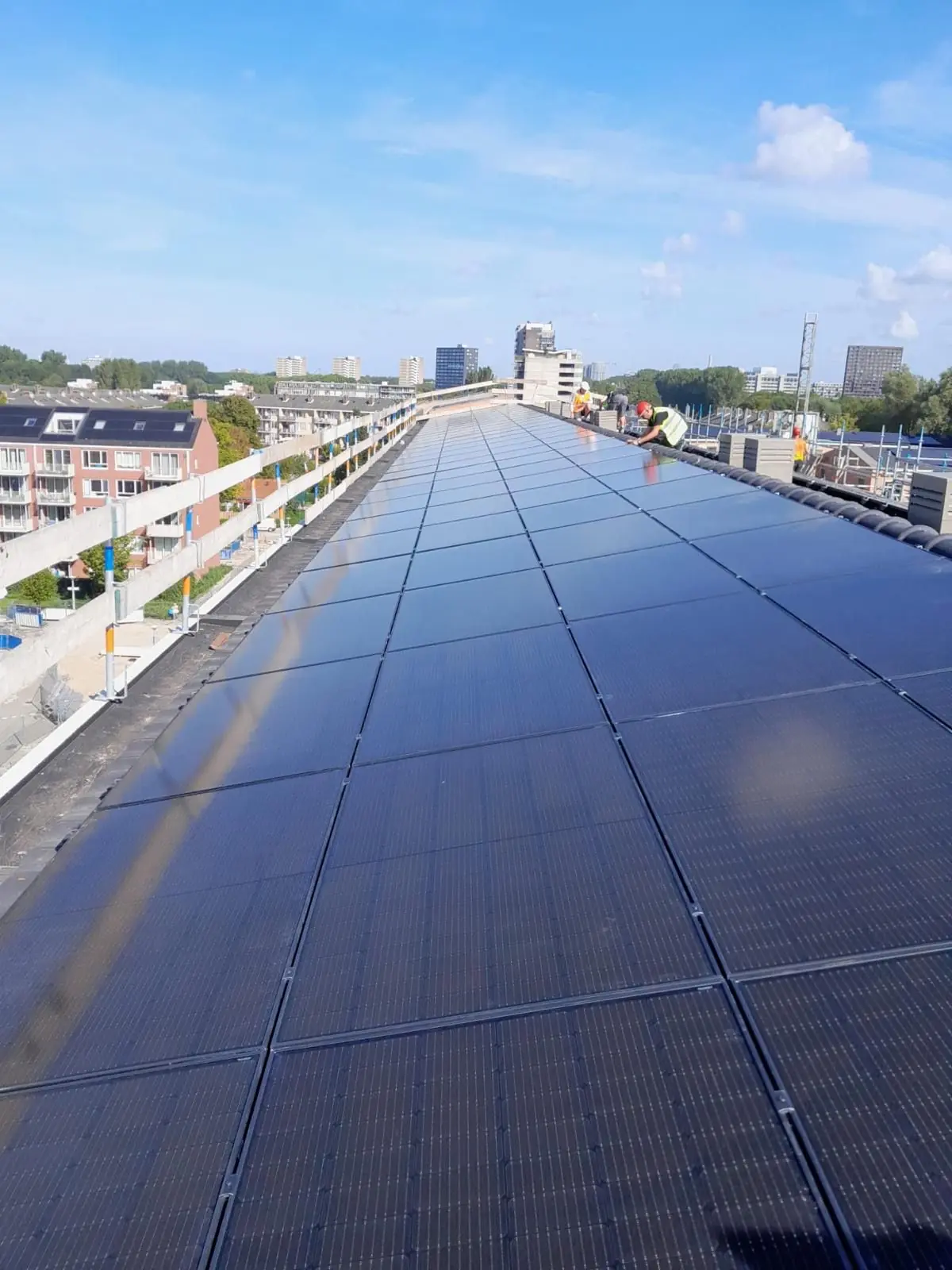 Montuotojai įrengia saulės elektrinę ant ilgo pramoninio stogo