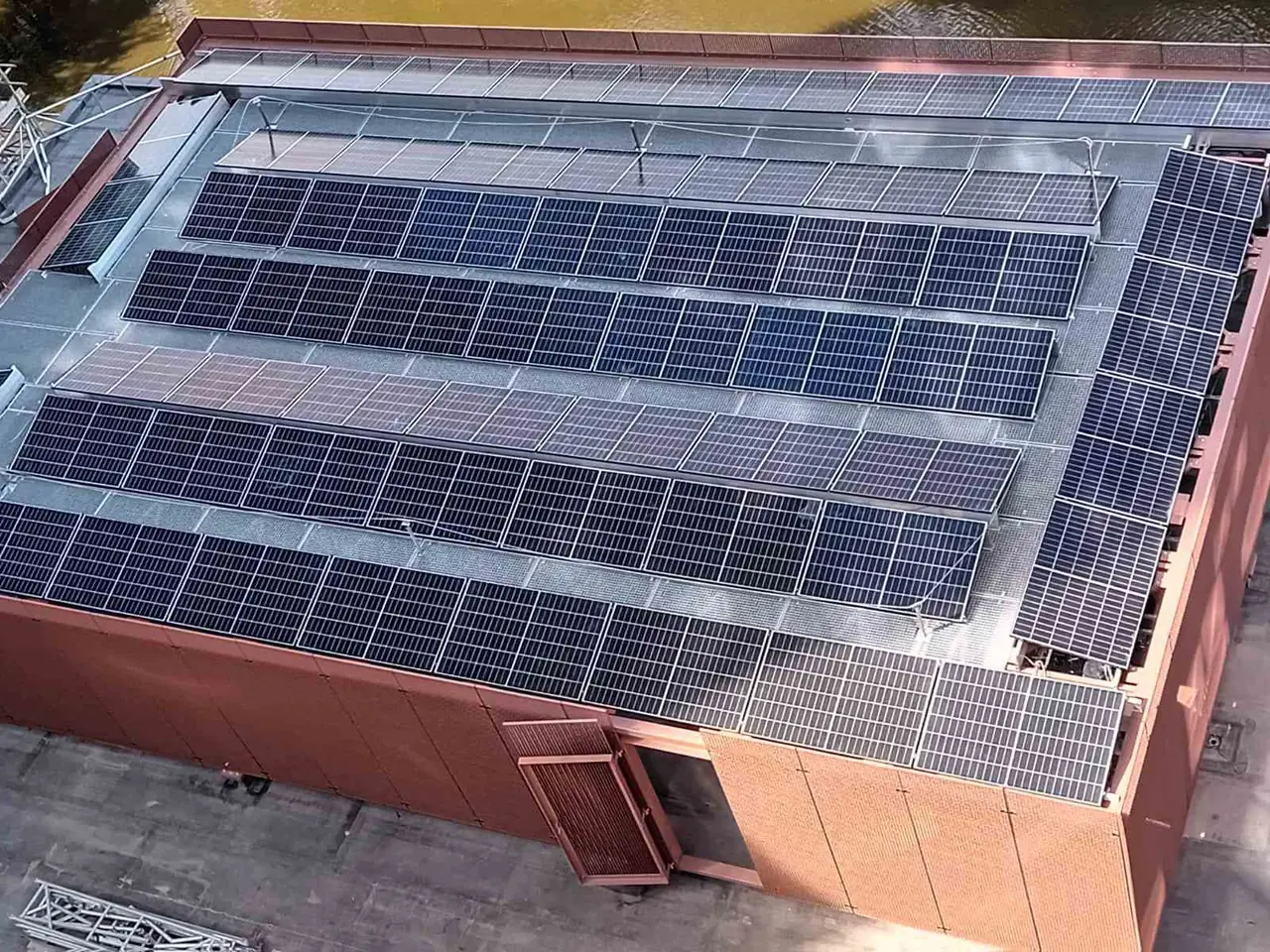 Saulės elektrinė ant pramoninio pastato stogo iš paukščio skrydžio